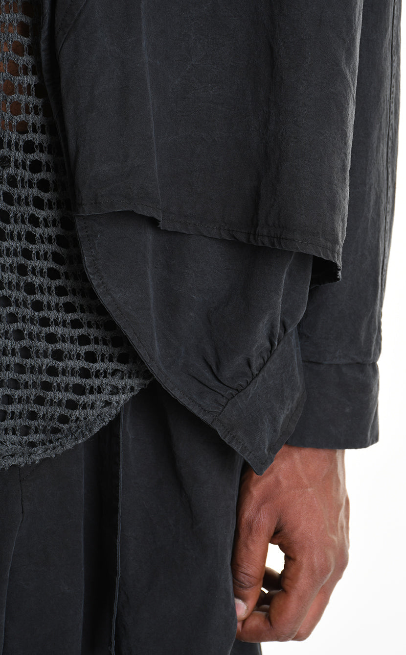 Close-up of a person wearing a dark gray shirt with rolled-up sleeves, holding a phone.