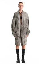 Woman wearing a long, textured coat with black boots on a white background