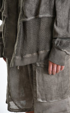 Person wearing a dark gray jacket and pants with a textured pattern, brand 'LA HAINE INSIDE US' visible.