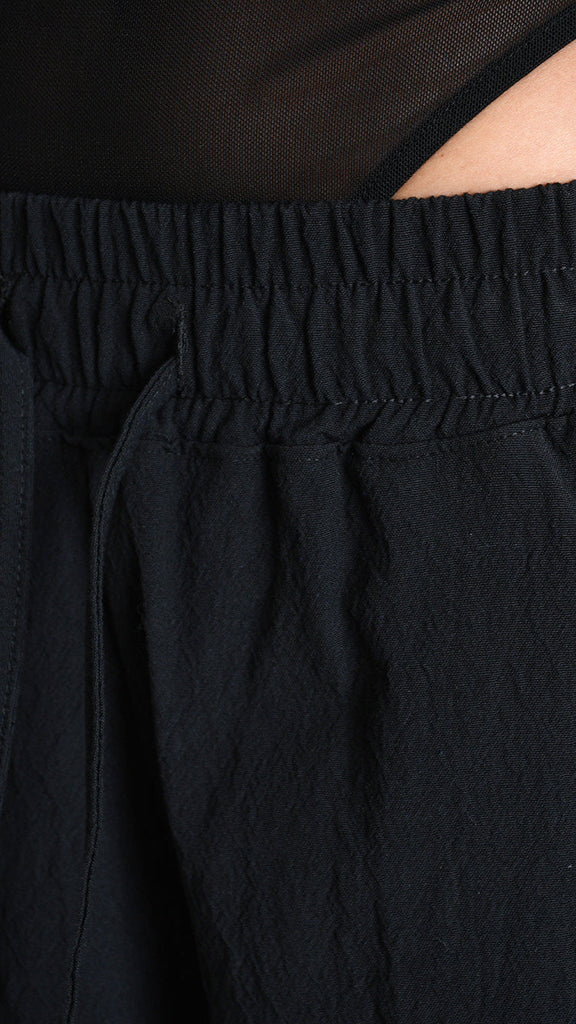 Baggy black cotton jacquard trouser with elastic waist and drawstring.