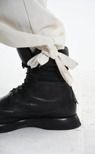 Black leather boots with white laces on a light background, featuring the text 'LA HAINE INSIDE US'.