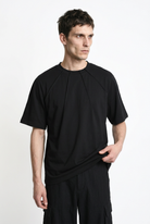 LA HAINE INSIDE US M1375 black oversized cotton stretch T-shirt, front view holding hem to show drape